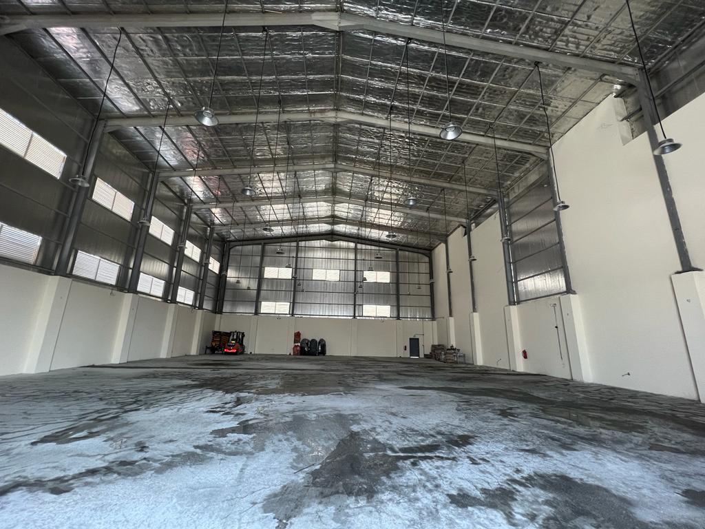Open warehouse interior with steel roof framing and suspended lights