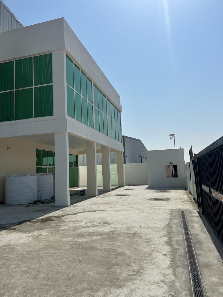 Warehouse office with green glazing beside a paved courtyard